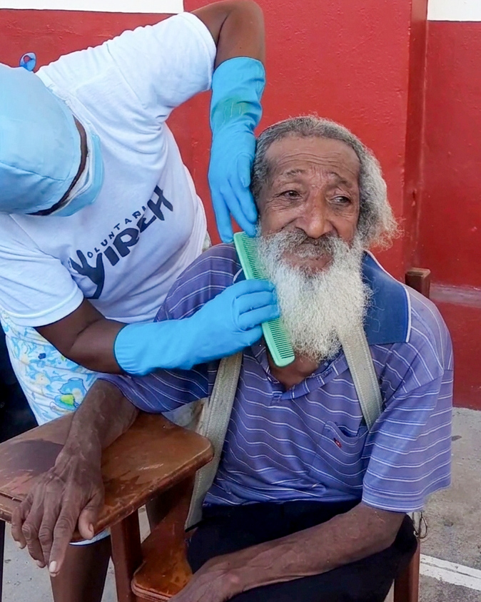 Voluntario peinando la barba de un homeless