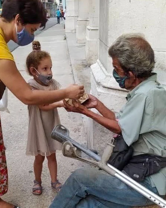 Madre y niña del proyecto Yireh dando alimentos a persona que vive en las calles