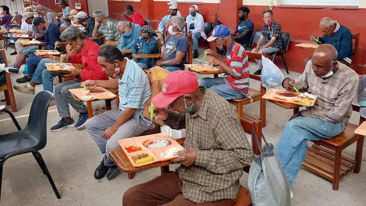 Personas sin hogar comiendo en la iglesia de la Víbora